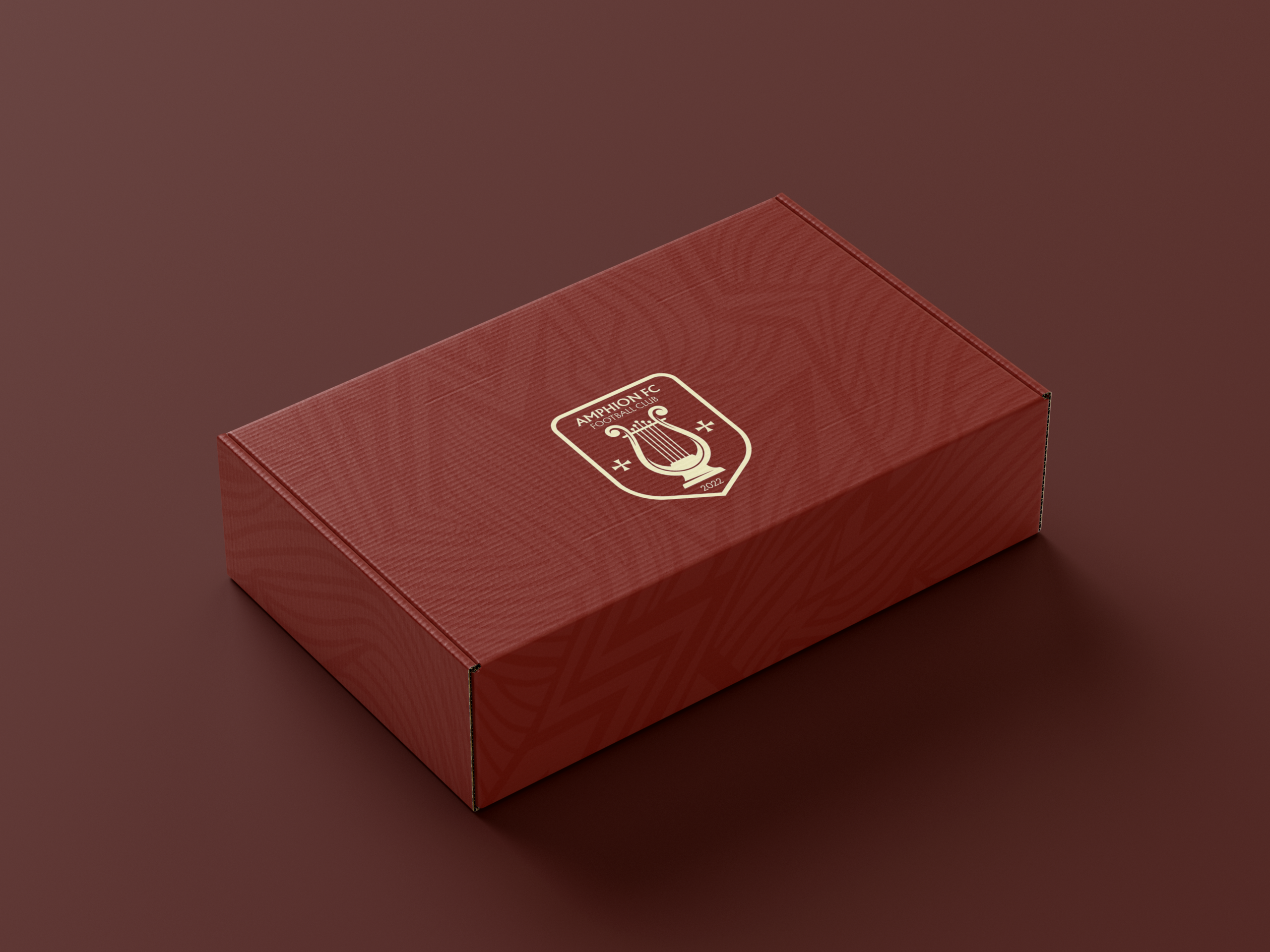 Boîte packaging premium maillot domicile Amphion FC bordeaux et or avec logo Lyre